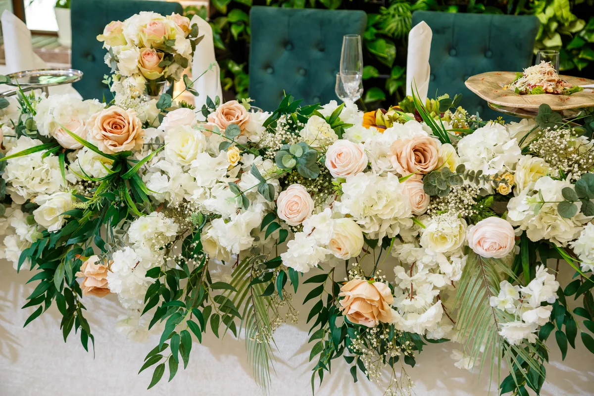 Flores Selecionadas para Casamentos e Eventos Distintos. Centro de mesa floral com hortênsias brancas, rosas em tons suaves e folhagens naturais para decoração de eventos.